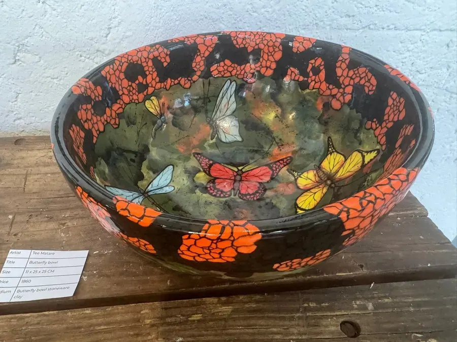 A stoneware bowl painted with orange flowers and butterflies