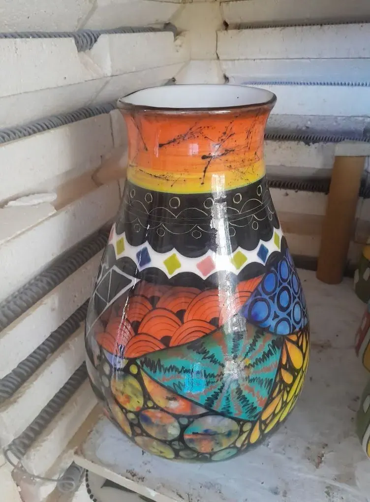 A tall vase painted with orange, blue and black patterns