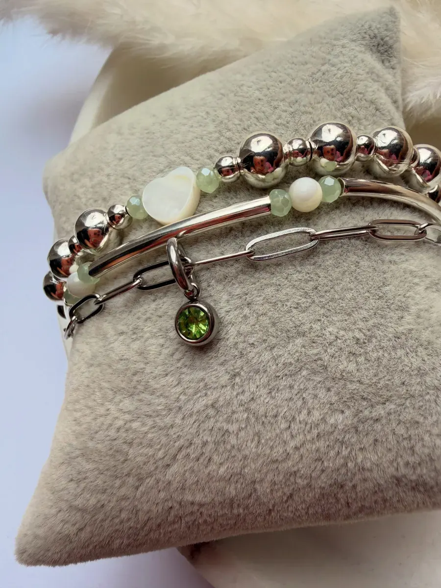 A bracelet stack with a peridot charm