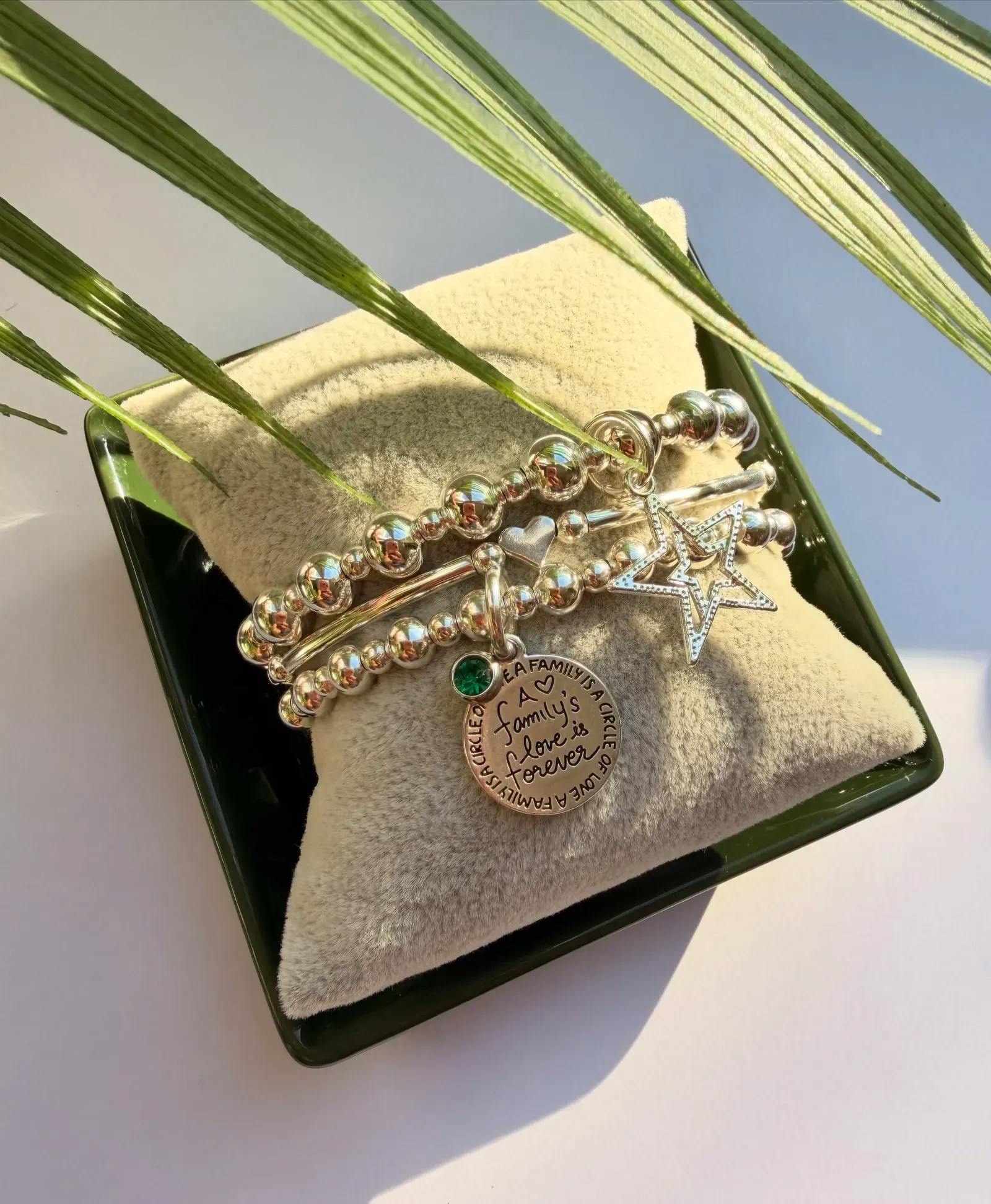 A stack of beaded and charm bracelets on a cushion
