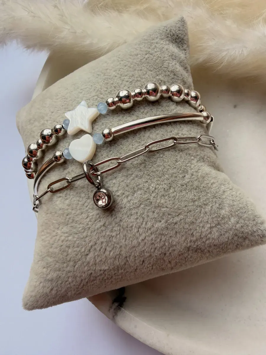 A stack of silver and pearl bracelets