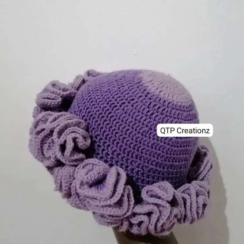 A purple crochet hat with rosettes