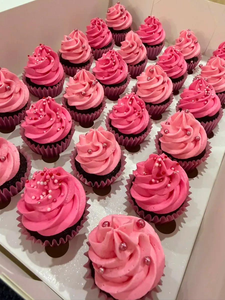 A tray of pink buttercream cupcakes